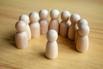 Beige Wooden Figures In Semi Circle Facing Center On Wooden Table