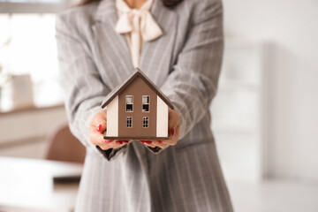 Female real estate agent with house model in office, closeup