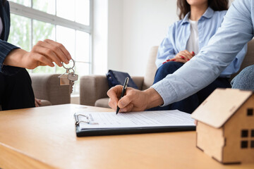Young couple with real estate agent buying house in room, closeup