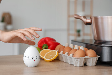 Female hand and modern kitchen timer with food on table in room, closeup