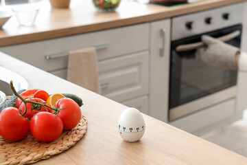 Modern kitchen timer on table against woman baking in room, closeup
