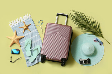 Composition with suitcase, photo camera, starfishes and beach accessories on green background