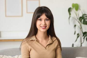 Smiling young woman sitting on sofa at home, closeup