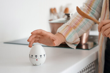 Woman with kitchen timer cooking on counter in room, closeup
