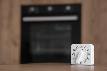 Kitchen timer on table against oven in room, closeup