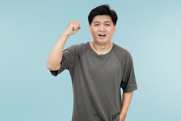 young asian man celebrating success in victory gesture in studio background
