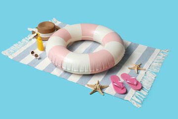 Inflatable ring, bottle of sunscreen cream and beach accessories on blue background, closeup
