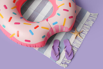 Inflatable ring and beach accessories on lilac background, closeup