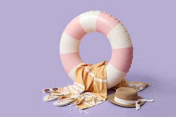 Inflatable ring and beach accessories on lilac background, closeup