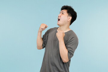 young asian man celebrating success in victory gesture in studio background