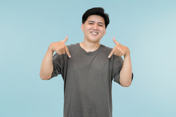 Naklejka premium young asian man pointing down gesture showing something in studio background