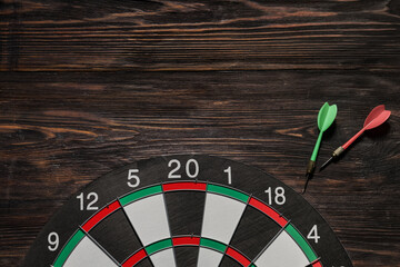 Board with darts on wooden  background