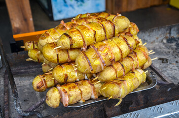 Mouth watering pile of whole potatoes with bacon, thinly sliced and skewered, ready for grilling or...
