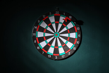 Board with dart hanging on green wall