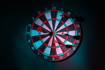 Board with darts hanging on dark wall