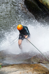 Latin american athlete rappelling down a waterfall, participating in the extreme sport of...