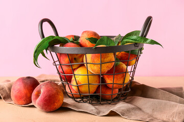 Basket of fresh peaches on pink background