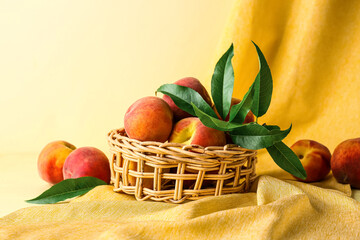 Wicker basket of fresh peaches on beige background