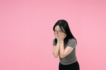 shy asian woman covering his face with hands in studio background