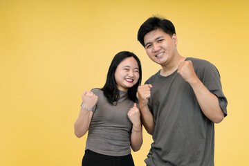 couple asian showing success gesture in studio yellow background