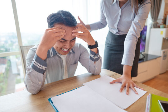 Indonesian southeast asian businessman gets scolded by his boss for being late or for the stress of deadlines. Paperwork on the table. Business concept