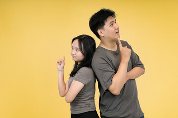 Couple Standing Back-to-Back pointing up in studio background