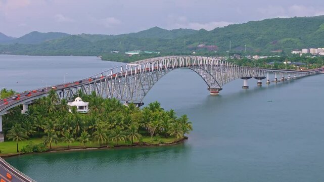 Aerial semi orbit around the iconic San Juanico Bridge between Leyte and Samar, Philippines. Calm waters and tropical greenery under partly cloudy sky.