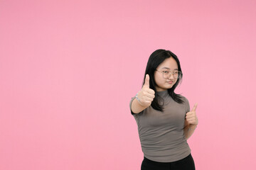 short asian woman giving double thumbs up with happy expression in pink background