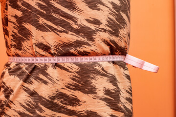 Young man measuring his waist with tape during a routine health checkup at home
