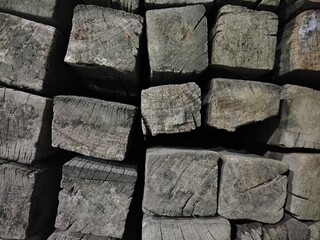 A close-up of stacked, weathered wooden beams showing natural textures, grain patterns, and cracks. Suitable for use in rustic-themed designs, backgrounds, or texture references in 3D modeling.