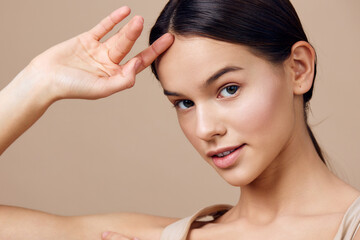 Naklejka premium Portrait of a young woman with a natural makeup look, demonstrating beauty and confidence against a soft beige background, perfect for beauty and skincare concepts