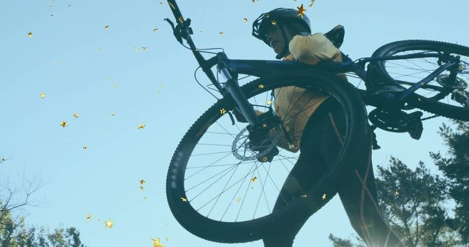 Cyclist approaching mountain bike hoisting it on shoulder while hiking uphill with golden particles
