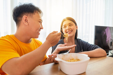 Indonesian southeast asian couple family eating noodles meal together in the dining room