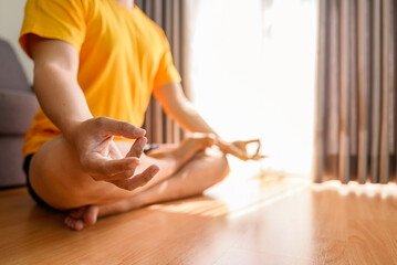Man meditating in the lotus position on yoga at home for a healthy lifestyle and body care. Meditation and yoga practices concept
