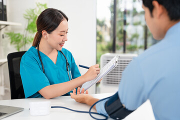 Female doctor in scrub uniform measure blood pressure with electronic monitor in hospital. Caring...