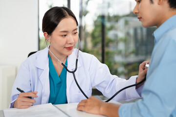 Asian doctor talk with patient about disease symptom, doctor use stethoscope listening lung of...