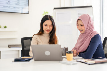 Multiracial young female employees work on laptop discuss business cooperation ideas at meeting...