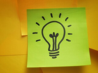 A hand-drawn lightbulb on a green sticky note, symbolizing creativity and innovation, with an...