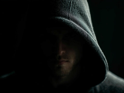 hooded man in dark room creates mysterious atmosphere with silhouette lighting, evoking intrigue and suspense