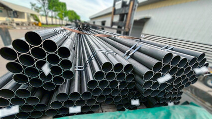 High-quality black steel pipes and square steel tubes stored at a construction site. Suitable for...