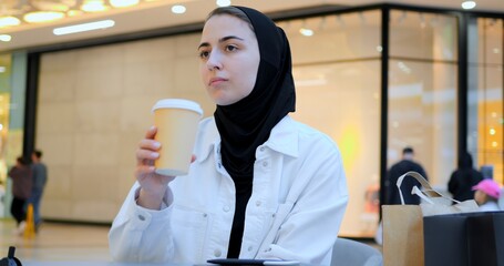 Young woman engaging with smartphone while enjoying coffee in trendy cafe, embodying modern digital connectivity and leisurely urban lifestyle during focused moment of communication