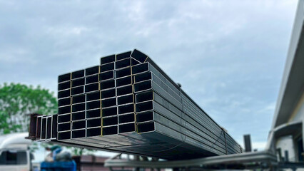 Fototapeta premium Metal Products on Truck Ready for Shipping.Assorted steel profiles including square tubes, and black steel pipes placed on a transport truck, distribution side of the steel industry.