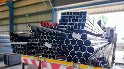 Steel pipes and structural steel shapes secured on a flatbed truck, prepared for delivery to...