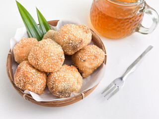 Crispy sesame-studded onde-onde in a bamboo basket, decorated with pandan leaves, a traditional sweet treat