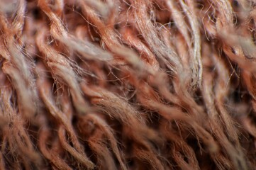 A detailed macro close-up of interwoven fibers and threads, showcasing the intricate texture of a soft, brown yarn or fabric