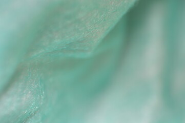 A macro shot capturing the soft and fluid texture of turquoise fabric with subtle folds and delicate gradients