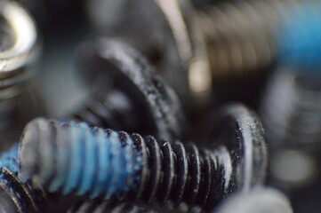 A detailed macro photograph showcasing an up-close view of screws with distinct blue and black hues