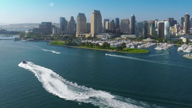 Breathtaking aerial shots capture the vibrant and lively downtown skyline of San Diego, showcasing boats gracefully navigating the calm waters below, creating a picturesque waterfront scene