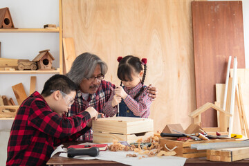 Asia retirement carpenter man spends time with cheerful granddaughter in carpentry studio, aged...
