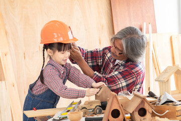 Asia retirement carpenter man spends time with cheerful granddaughter in carpentry studio, aged people enjoy teaching woodwork skill to adorable niece, family hobby lifestyle parenthood DIY handmade